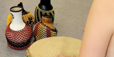 Een persoon zit achter een djembé op de grond staan percussie instrumenten