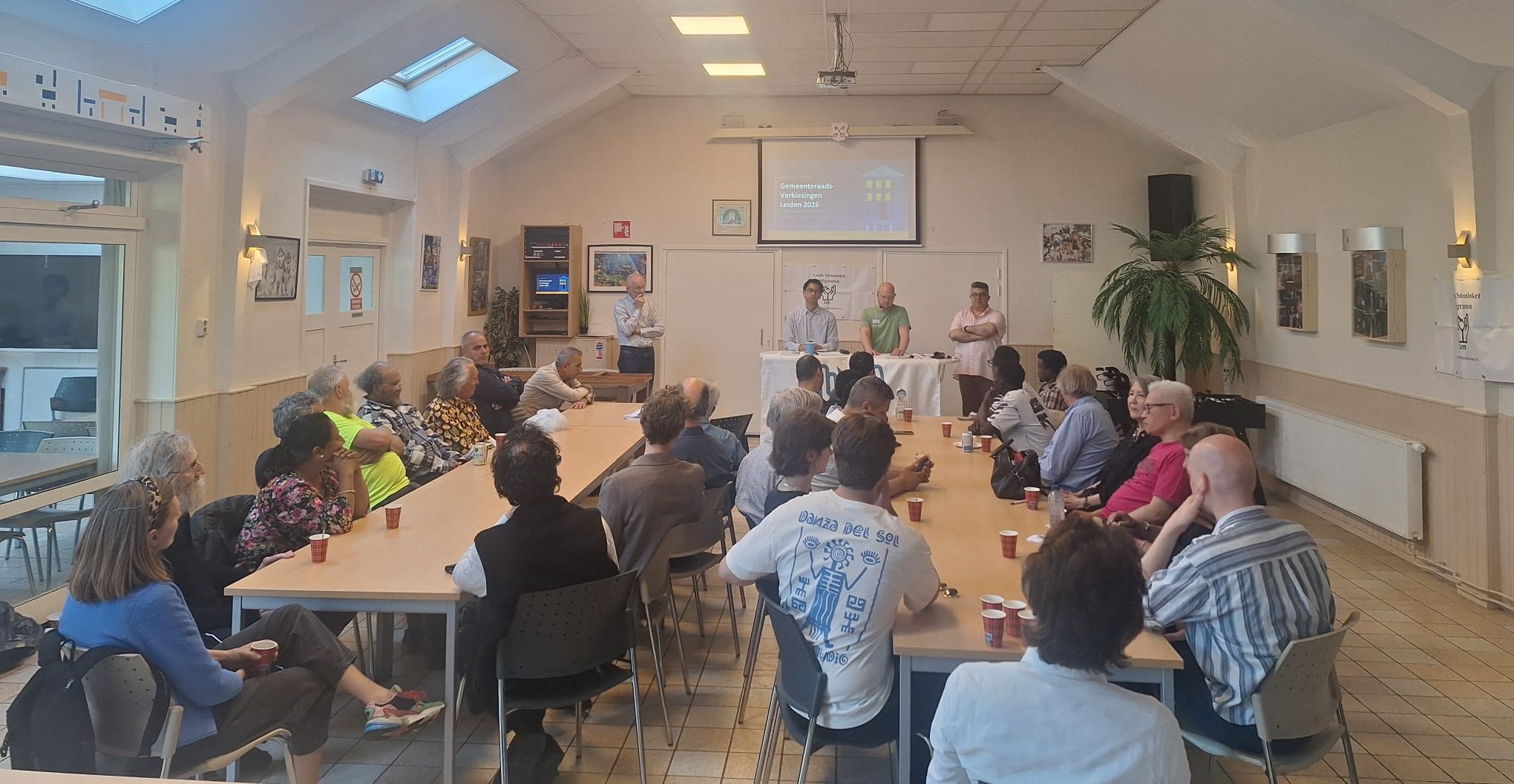 Bewooners zitten rond twee tafels tijdens de informatieavond