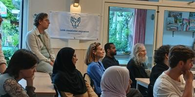 Mensen luisteren met aandacht aan een toespraak tijdens de informatieavond van het Leids Steunloket Migranten